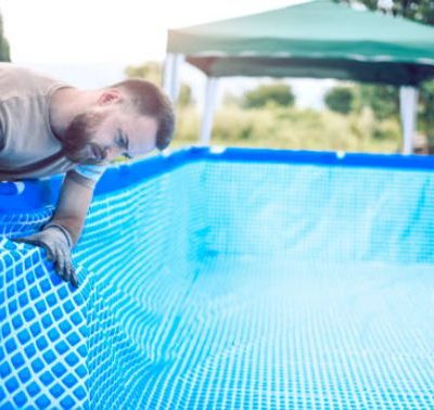 hombre revisando fugas de agua en la piscina de color azul y forma cuadrada